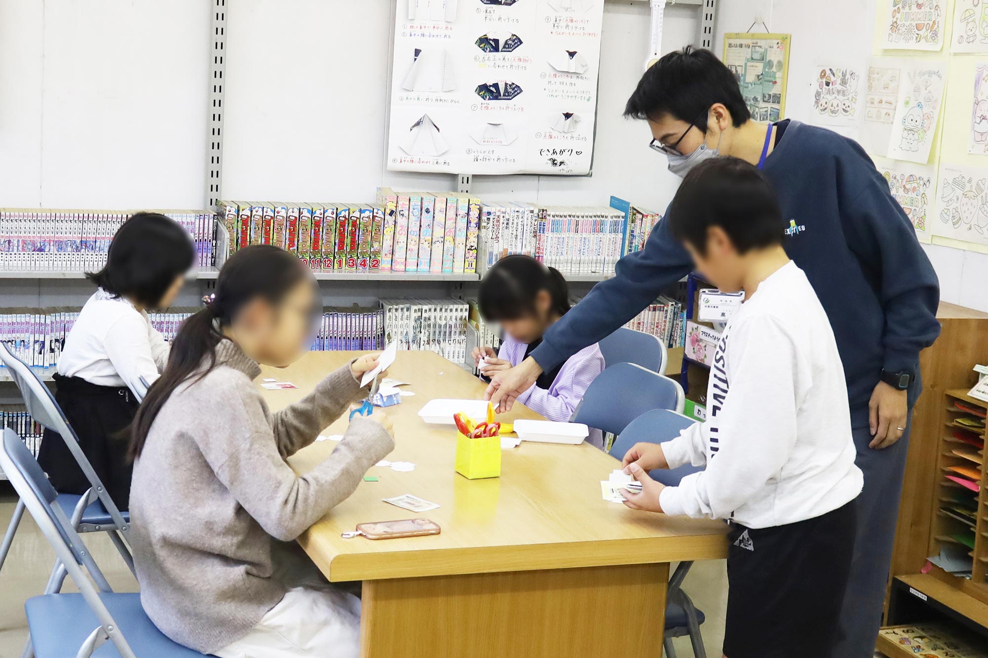 こどもたちに工作の方法を教えるスタッフ