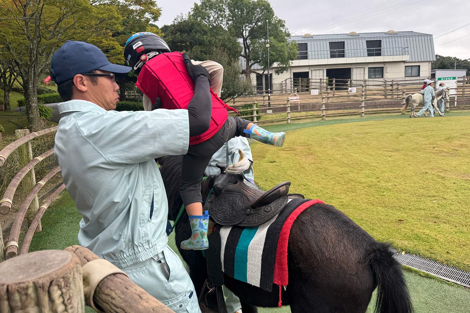 スタッフの手を借りて野間馬に乗ろうとするこども