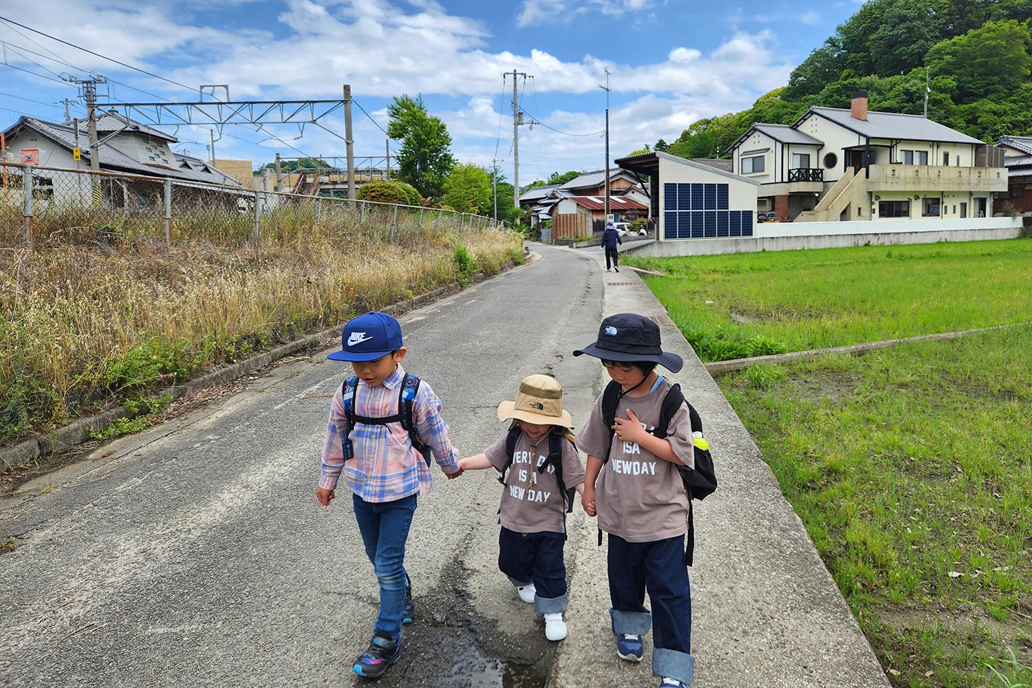 こども3人が手をつないで道を歩いている様子