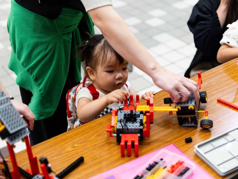 ブロックのロボットにふれるこどもの写真